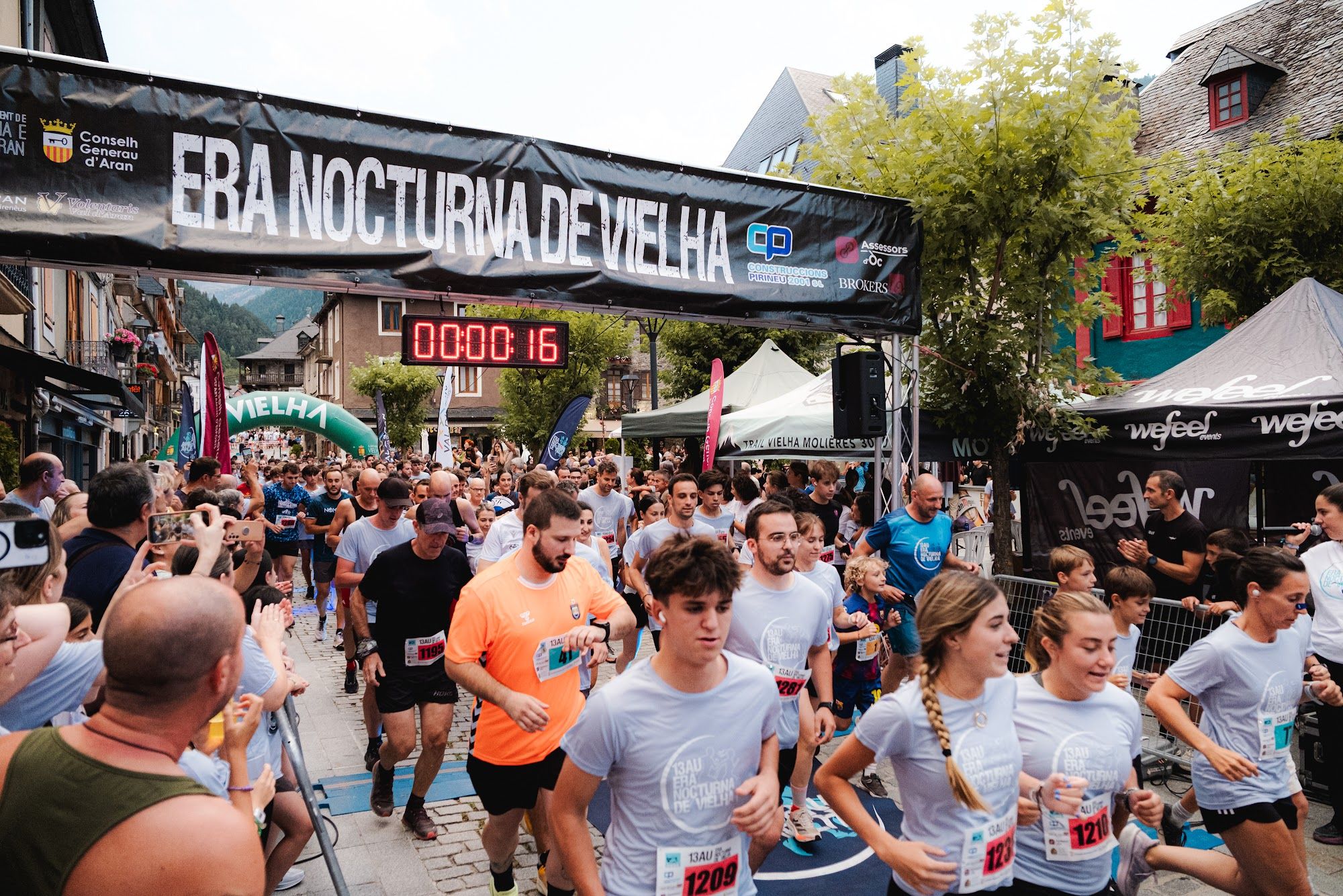 Salida masiva de la carrera bajo el arco y la pancarta de Era Nocturna de Vielha